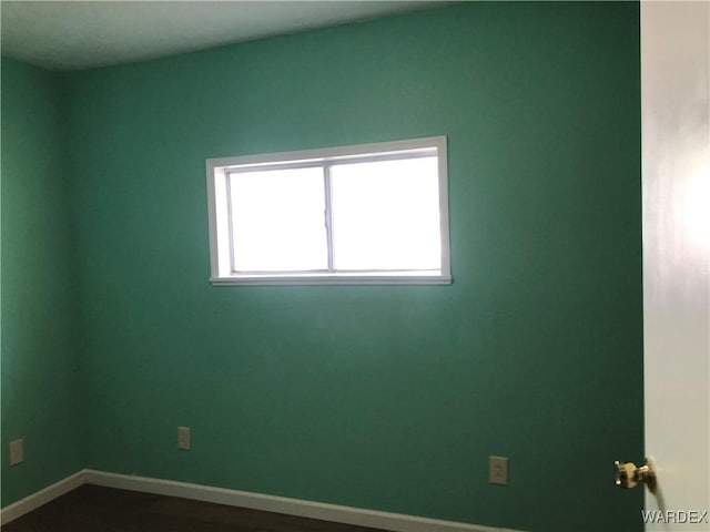 unfurnished room featuring dark wood-style floors and baseboards