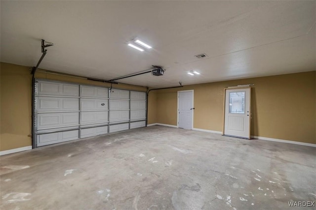 garage with a garage door opener, visible vents, and baseboards