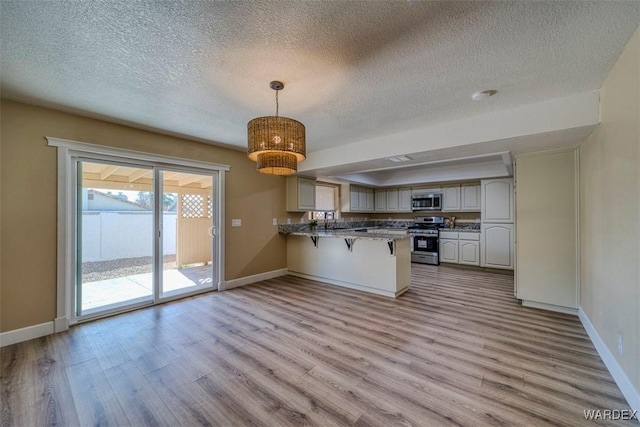 kitchen featuring a peninsula, light wood-style flooring, appliances with stainless steel finishes, and a breakfast bar