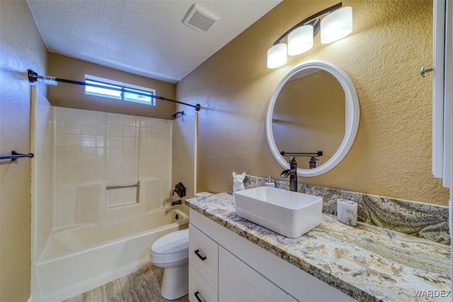 full bath with shower / bath combination, visible vents, toilet, and a textured wall