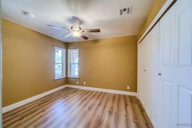 unfurnished bedroom featuring baseboards, visible vents, light wood-style flooring, and a closet