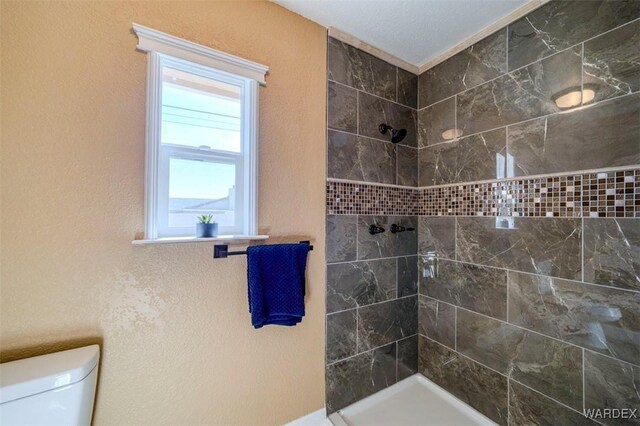 full bath featuring a textured wall, a shower stall, and toilet