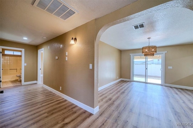 foyer with arched walkways, light wood-style flooring, and visible vents