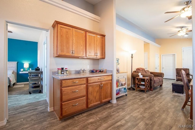 kitchen featuring dark wood-style flooring, a ceiling fan, open floor plan, light countertops, and brown cabinetry