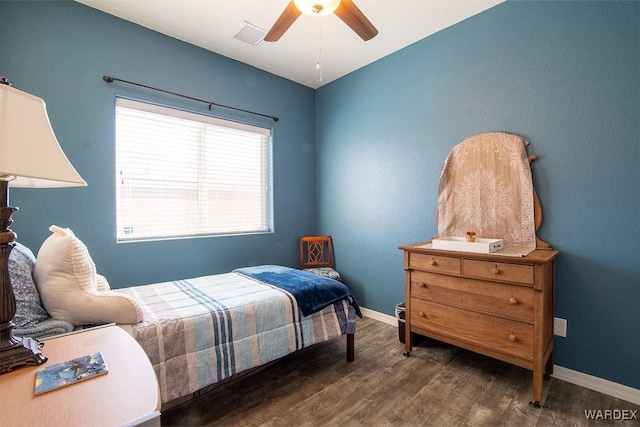 bedroom with a ceiling fan, visible vents, baseboards, and wood finished floors