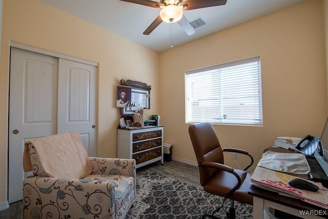 office featuring baseboards, visible vents, dark wood-style flooring, and a ceiling fan