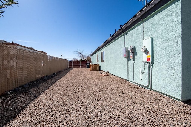 view of side of property with a fenced backyard and stucco siding