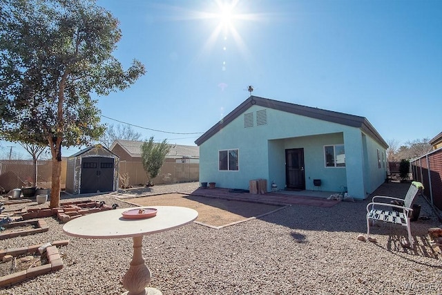 rear view of property with a patio area, a fenced backyard, a storage unit, and an outbuilding