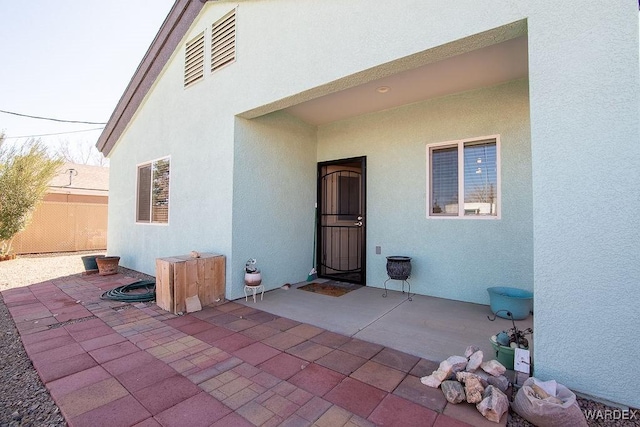 doorway to property featuring a patio, fence, and stucco siding