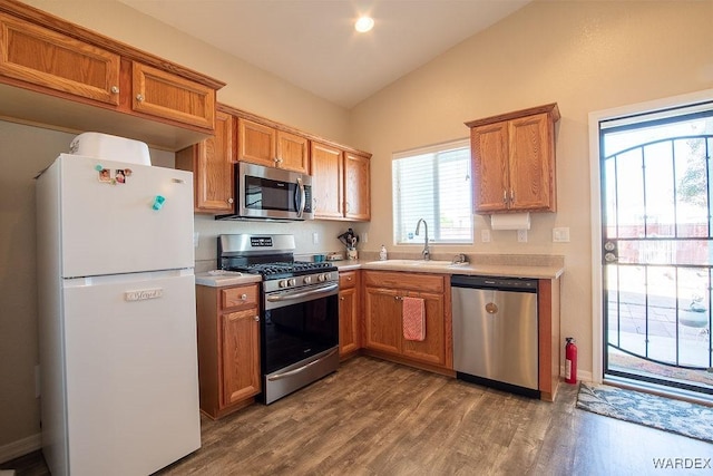 kitchen with dark wood-style floors, stainless steel appliances, lofted ceiling, light countertops, and a sink