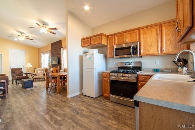 kitchen with lofted ceiling, brown cabinets, wood finished floors, stainless steel appliances, and a sink