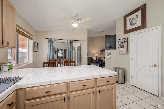 kitchen with a ceiling fan, light tile patterned floors, tile countertops, and light brown cabinetry