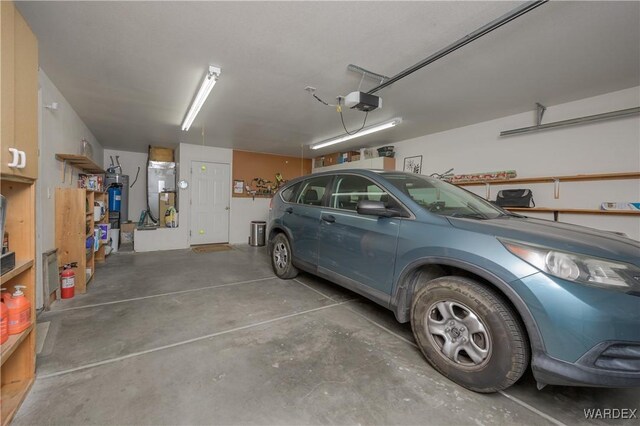 garage featuring heating unit, water heater, and a garage door opener