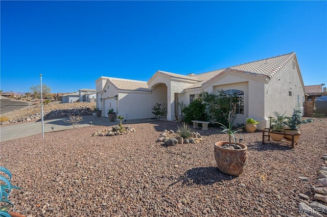 view of front of house with driveway, an attached garage, a tiled roof, and stucco siding