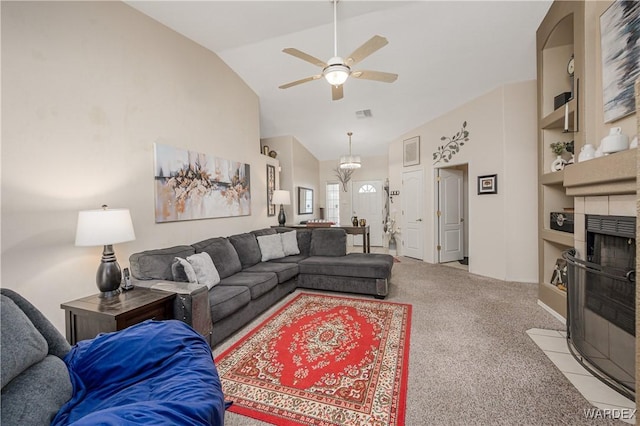 living area with visible vents, a tiled fireplace, light colored carpet, ceiling fan, and high vaulted ceiling