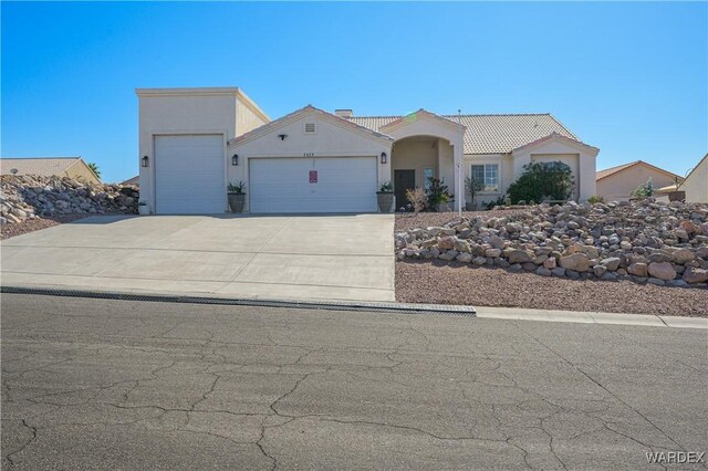 view of front of property with driveway, a tiled roof, an attached garage, and stucco siding