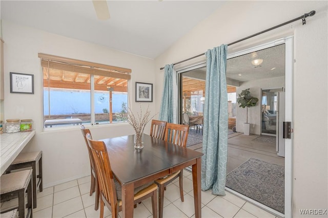 dining space featuring vaulted ceiling, light tile patterned flooring, and baseboards