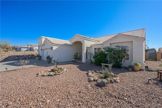 view of front of house with an attached garage, driveway, a tiled roof, and stucco siding