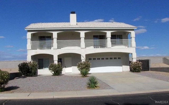 view of front facade with a garage, a tile roof, driveway, and stucco siding