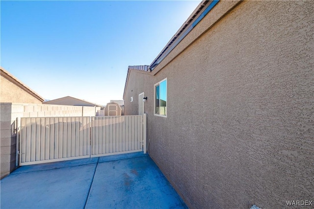 exterior space featuring a gate, fence, and stucco siding