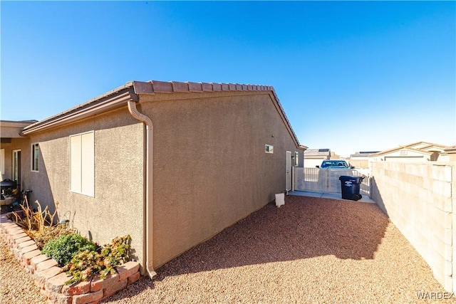 view of side of property featuring fence and stucco siding