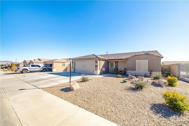 ranch-style home with concrete driveway, an attached garage, and stucco siding