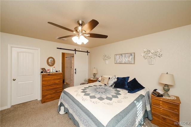 carpeted bedroom featuring a ceiling fan, visible vents, and a barn door