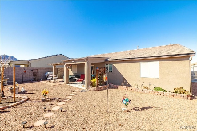 rear view of house featuring a fenced backyard, a patio, and stucco siding