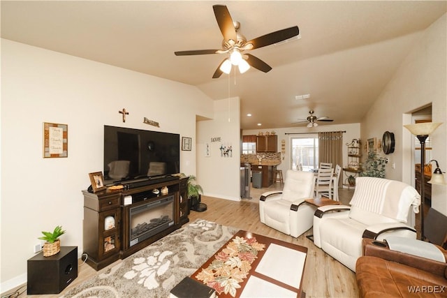 living room with lofted ceiling, ceiling fan, baseboards, and light wood-style floors