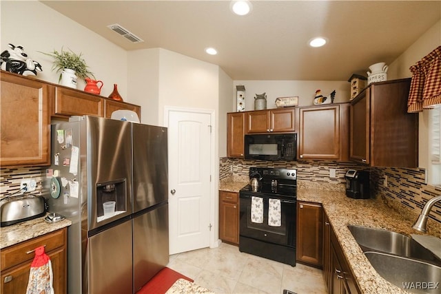 kitchen with light stone counters, visible vents, backsplash, a sink, and black appliances