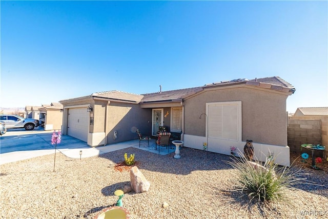 view of front of home with a garage, driveway, a patio, and stucco siding