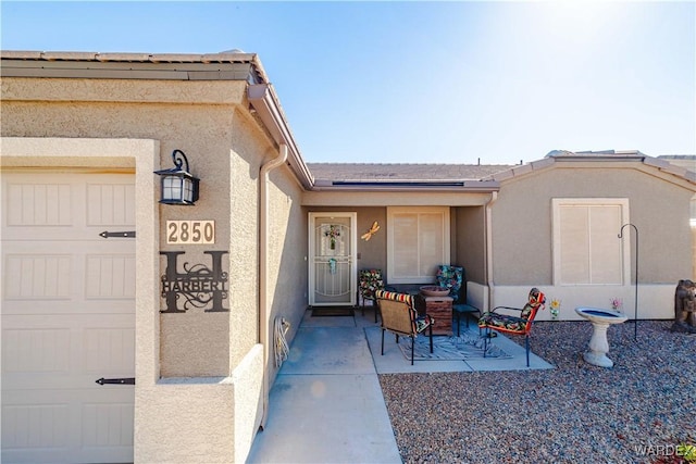 doorway to property with a garage and stucco siding