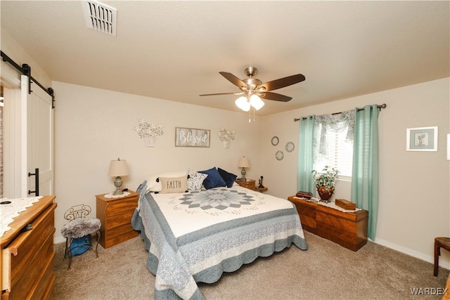 carpeted bedroom with visible vents, ceiling fan, baseboards, and a barn door