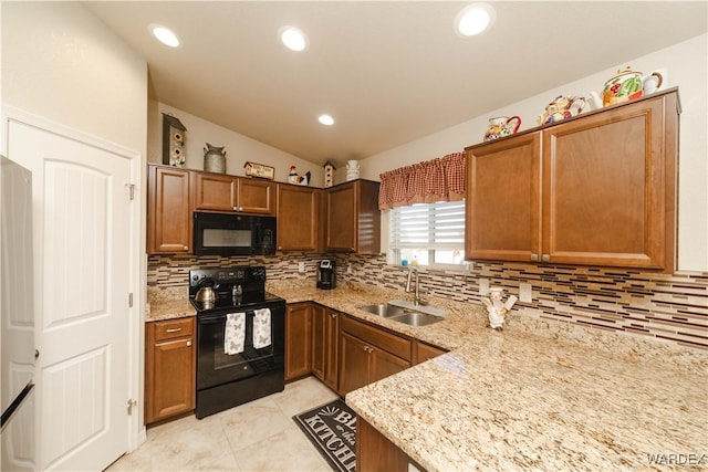 kitchen featuring light stone counters, tasteful backsplash, vaulted ceiling, a sink, and black appliances