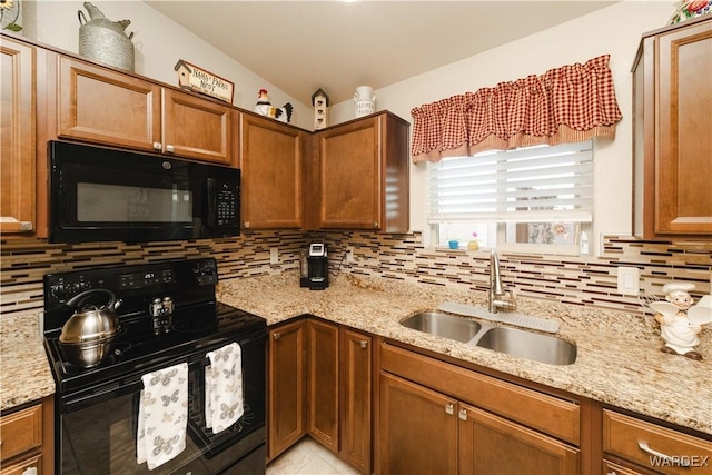 kitchen featuring a sink, light stone countertops, black appliances, tasteful backsplash, and brown cabinetry