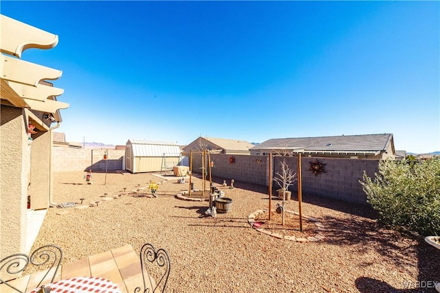 view of yard featuring a fenced backyard, a storage unit, and an outdoor structure