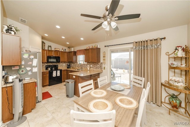 kitchen with brown cabinets, visible vents, backsplash, vaulted ceiling, and black appliances