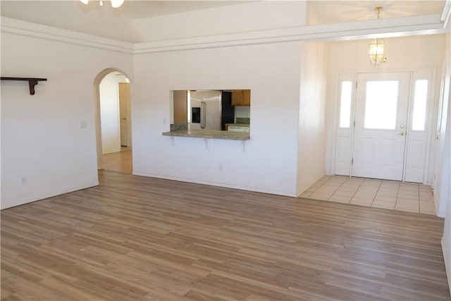 foyer with arched walkways and wood finished floors