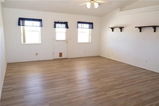 empty room with vaulted ceiling, a ceiling fan, and wood finished floors
