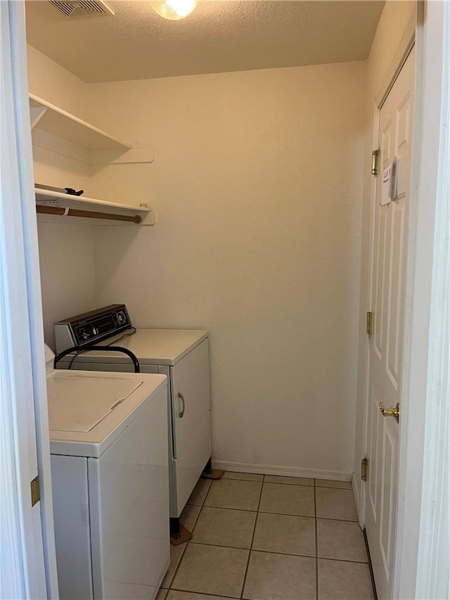 clothes washing area with washer and dryer, baseboards, and light tile patterned flooring