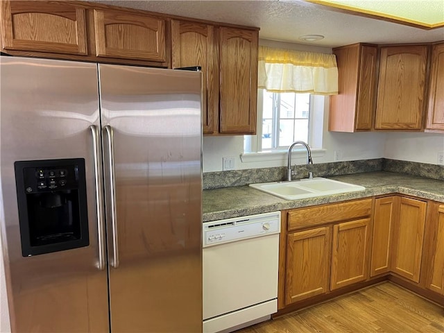kitchen with stainless steel fridge, dishwasher, a sink, and brown cabinets