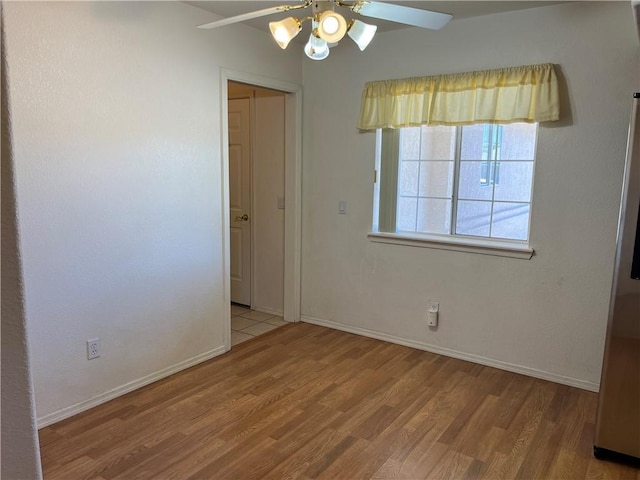 spare room with a ceiling fan, wood finished floors, and baseboards