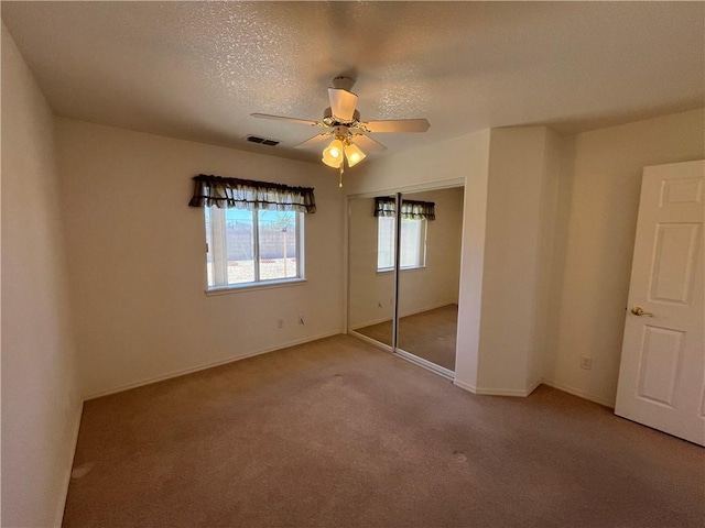 unfurnished bedroom with carpet floors, a textured ceiling, a closet, ceiling fan, and baseboards