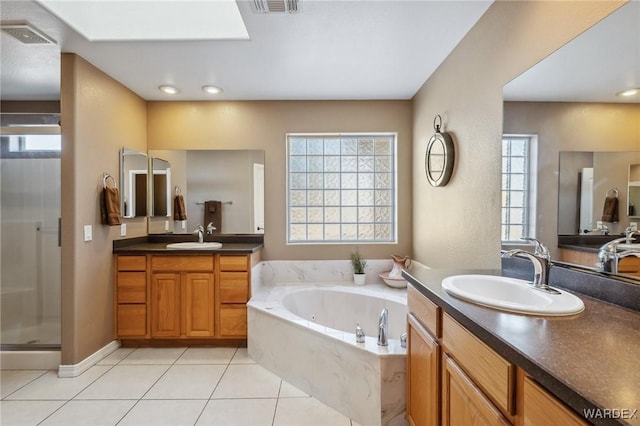 full bathroom featuring a stall shower, a garden tub, a sink, and tile patterned floors