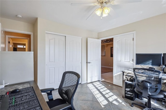 tiled office space featuring ceiling fan and baseboards