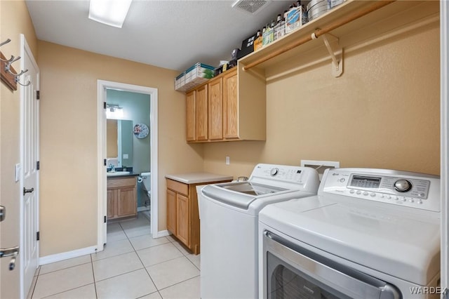 laundry room featuring light tile patterned floors, cabinet space, visible vents, washing machine and dryer, and baseboards