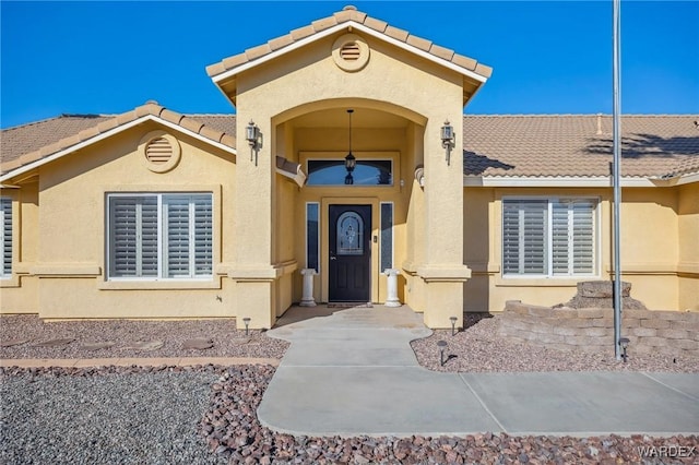 view of exterior entry featuring a tile roof and stucco siding