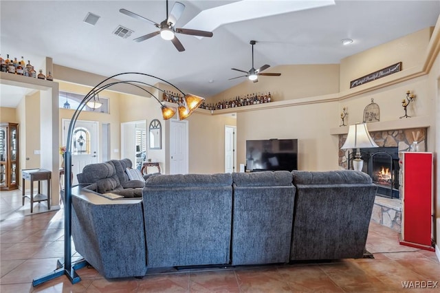 tiled living room featuring visible vents, vaulted ceiling, a fireplace, and ceiling fan