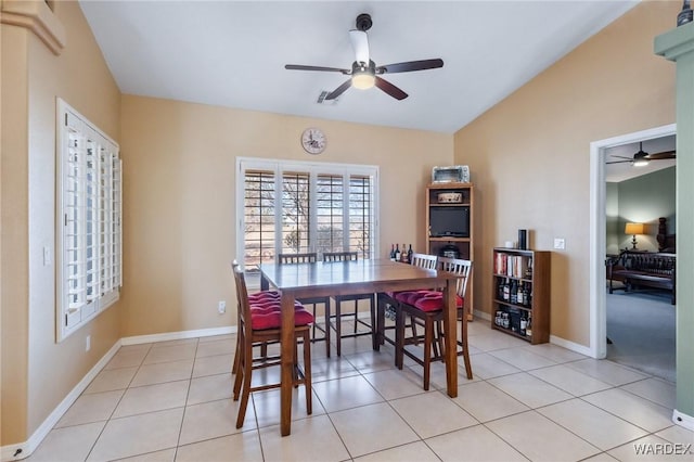 dining area with a ceiling fan, lofted ceiling, baseboards, and light tile patterned floors