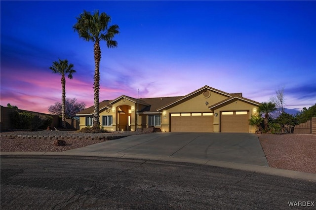 view of front of house featuring a garage, driveway, fence, and stucco siding